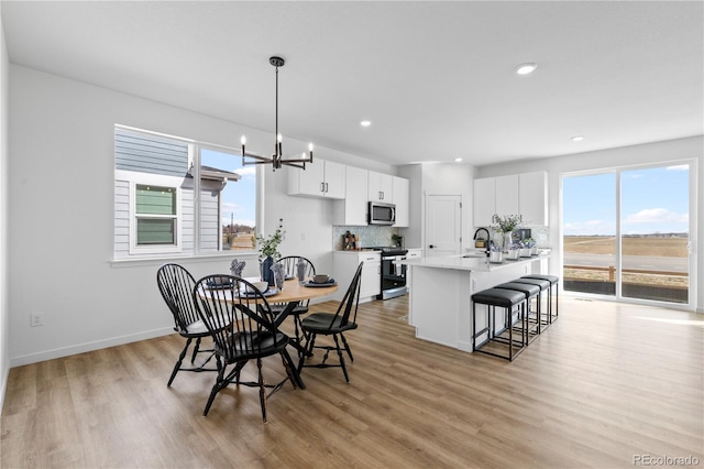 dining room featuring light wood-type flooring, recessed lighting, a chandelier, and baseboards