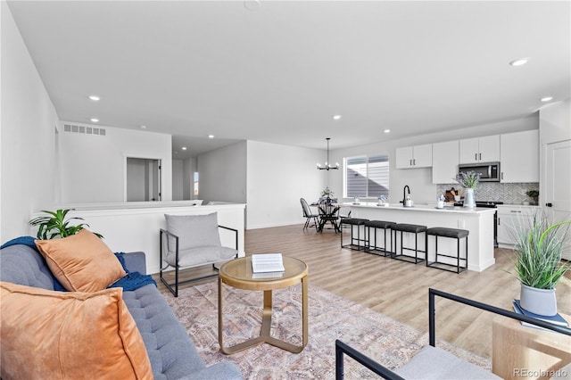 living room featuring recessed lighting, light wood-type flooring, and baseboards