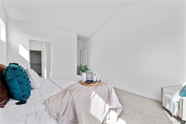 carpeted bedroom featuring vaulted ceiling, baseboards, and a walk in closet