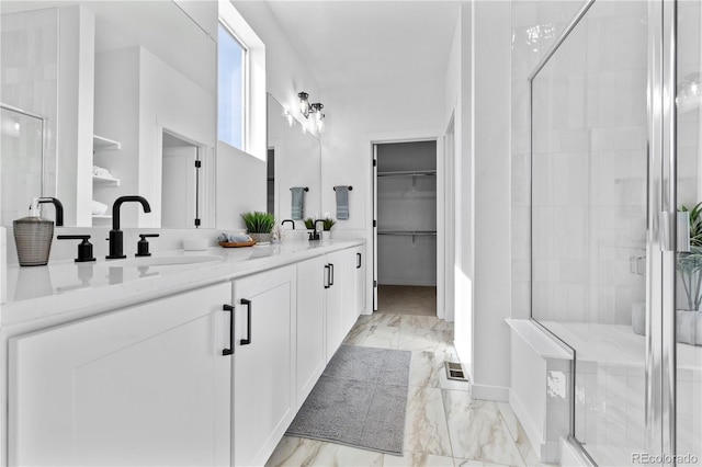 bathroom with marble finish flooring, a stall shower, a spacious closet, and double vanity