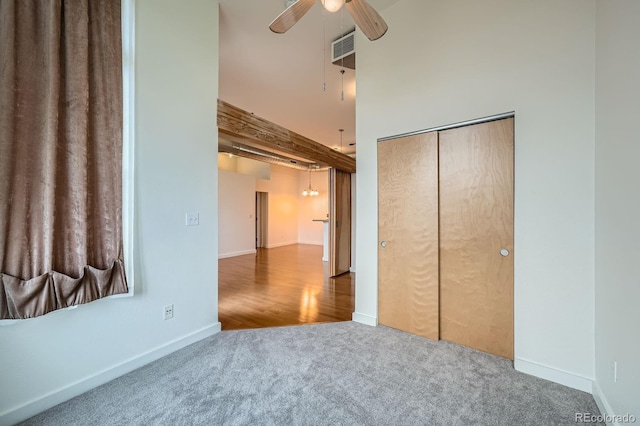 unfurnished bedroom featuring baseboards, carpet flooring, a closet, and a high ceiling