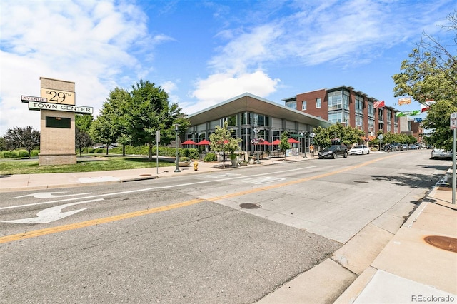 view of road with traffic signs, curbs, sidewalks, and street lights