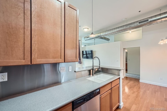 kitchen featuring stainless steel dishwasher, light wood finished floors, visible vents, a sink, and light countertops