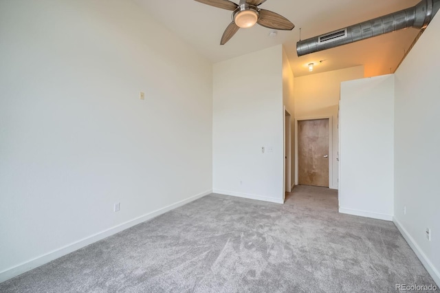 carpeted spare room with a towering ceiling, baseboards, a ceiling fan, and visible vents