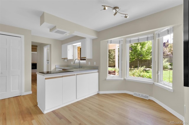 7504 E Jefferson Dr, Denver, CO 80237 - kitchen with a sink, white cabinets, light wood finished floors, baseboards, and a peninsula