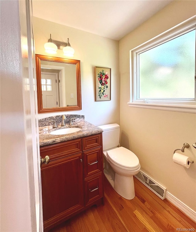7504 E Jefferson Dr, Denver, CO 80237 - half bathroom featuring wood finished floors, toilet, vanity, and baseboards
