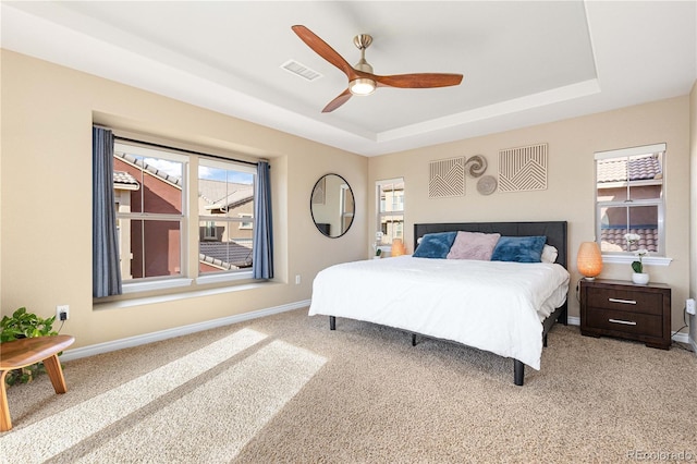 bedroom with a tray ceiling, ceiling fan, and carpet