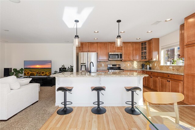 9228 Sori Ln, Highlands Ranch, CO 80126 - kitchen featuring stainless steel appliances, brown cabinets, backsplash, glass insert cabinets, and a kitchen bar