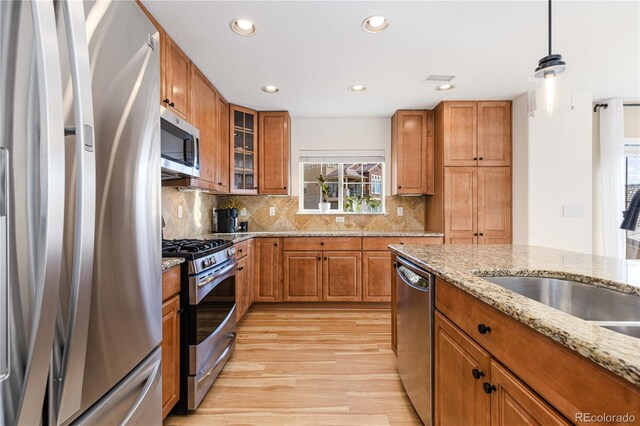 9228 Sori Ln, Highlands Ranch, CO 80126 - kitchen featuring stainless steel appliances, a sink, light wood-style floors, brown cabinets, and recessed lighting