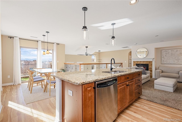 9228 Sori Ln, Highlands Ranch, CO 80126 - kitchen with dishwasher, a sink, open floor plan, brown cabinets, and light wood-type flooring