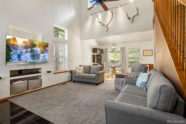 tiled living room with ceiling fan with notable chandelier and a towering ceiling