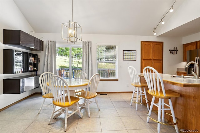 dining area with lofted ceiling, sink, light tile patterned floors, and a chandelier