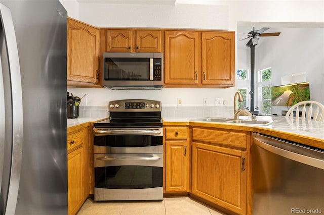 kitchen featuring sink, light tile patterned floors, ceiling fan, and appliances with stainless steel finishes