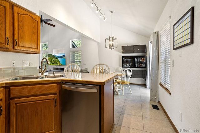 kitchen featuring lofted ceiling, sink, hanging light fixtures, light tile patterned floors, and dishwasher