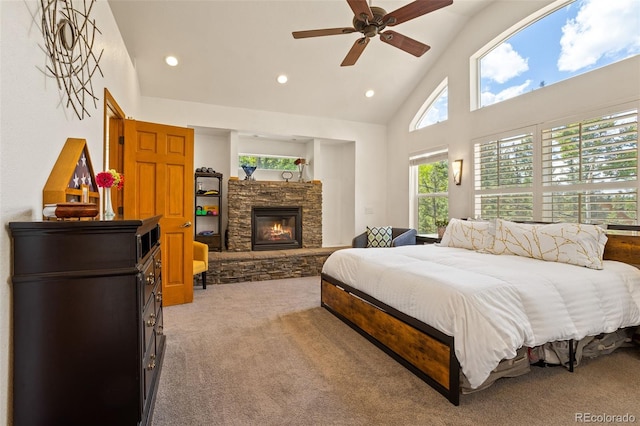 bedroom featuring light colored carpet, a fireplace, high vaulted ceiling, and ceiling fan