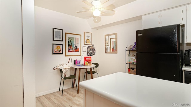 kitchen with ceiling fan, white cabinetry, light hardwood / wood-style floors, black fridge, and vaulted ceiling