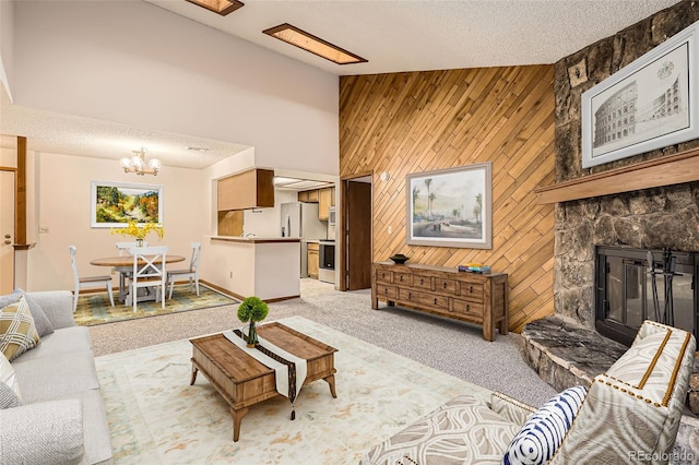 living room with high vaulted ceiling, wood walls, a fireplace, and light colored carpet