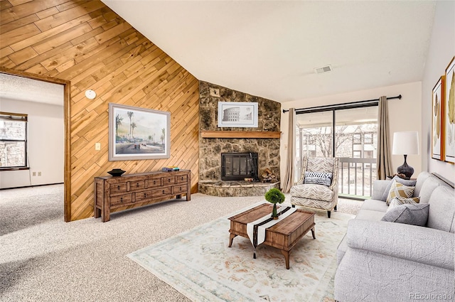 carpeted living room with a healthy amount of sunlight, wooden walls, a fireplace, and vaulted ceiling