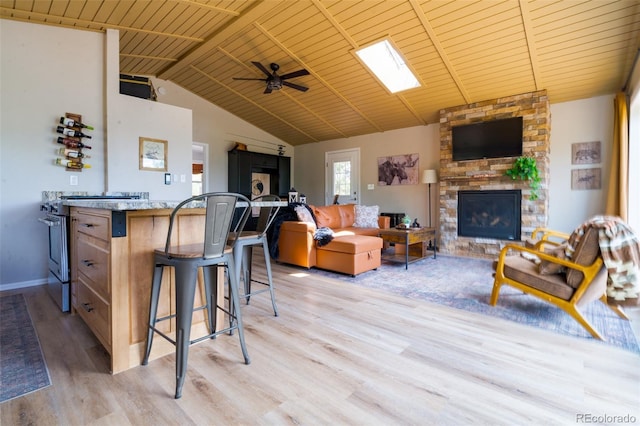 1040 Sheep Ridge Rd, Fairplay, CO 80440 - living area featuring light wood-type flooring, wooden ceiling, a stone fireplace, vaulted ceiling, and a ceiling fan