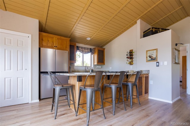 1040 Sheep Ridge Rd, Fairplay, CO 80440 - kitchen featuring freestanding refrigerator, wooden ceiling, light wood-style flooring, a peninsula, and a breakfast bar