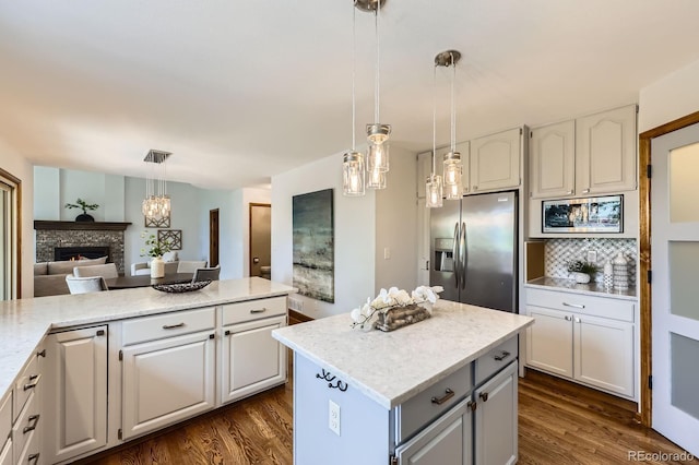 16247 E Belleview Pl, Centennial, CO 80015 - kitchen with stainless steel fridge, dark wood finished floors, a center island, and a lit fireplace