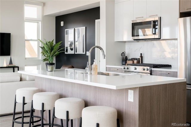 2880 Zuni St Unit 404, Denver, CO 80211 - kitchen with stainless steel appliances, modern cabinets, white cabinets, light countertops, and a breakfast bar area