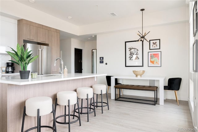 2880 Zuni St Unit 404, Denver, CO 80211 - kitchen featuring freestanding refrigerator, light countertops, a breakfast bar area, light wood-style floors, and modern cabinets