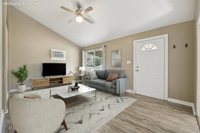 living room with ceiling fan, lofted ceiling, a wall unit AC, and light hardwood / wood-style flooring