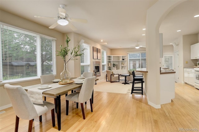 490 Jackson St, Denver, CO 80206 - dining space featuring ceiling fan, light wood-style floors, a fireplace, arched walkways, and baseboards