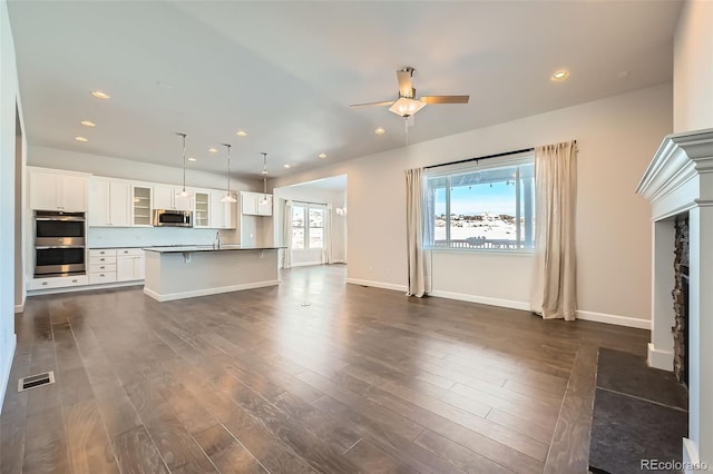 unfurnished living room featuring sink, ceiling fan, and dark hardwood / wood-style flooring