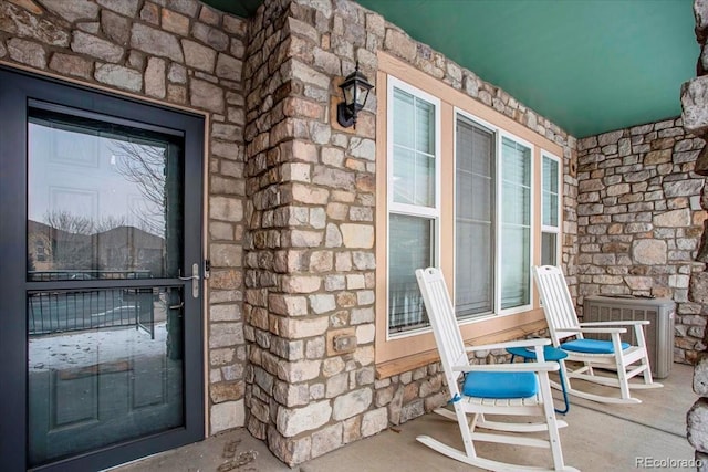 view of exterior entry with covered porch and central AC