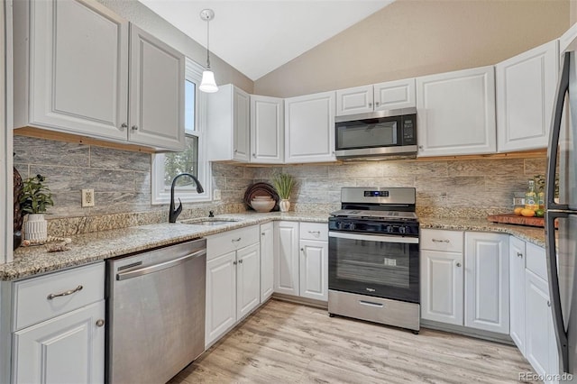 kitchen featuring white cabinets, stainless steel appliances, a sink, and lofted ceiling