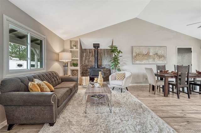 living area with lofted ceiling, built in shelves, wood finished floors, and a wood stove