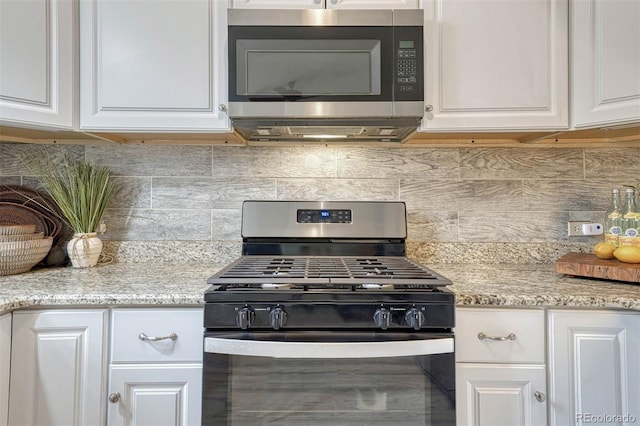 kitchen with decorative backsplash, white cabinets, light stone countertops, and stainless steel appliances