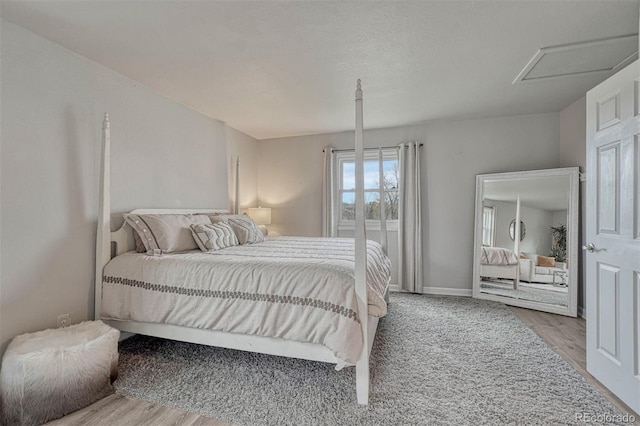 bedroom with baseboards, wood finished floors, and attic access