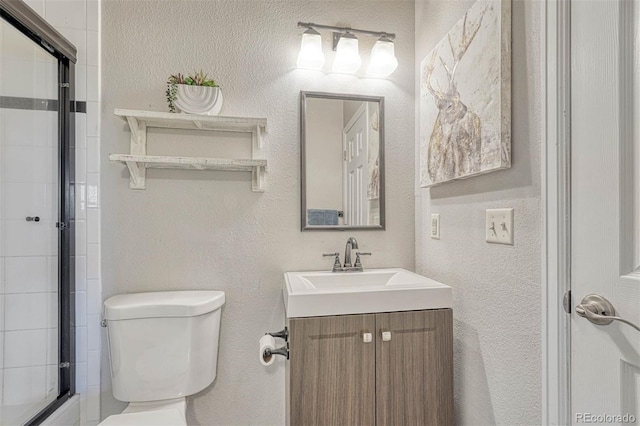 bathroom featuring an enclosed shower, toilet, a textured wall, and vanity