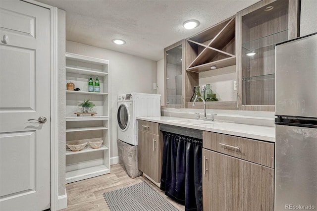 laundry area featuring a sink, washer / clothes dryer, light wood-type flooring, and a textured ceiling