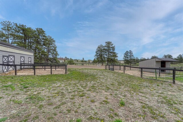 view of yard featuring an outdoor structure, an exterior structure, and a rural view