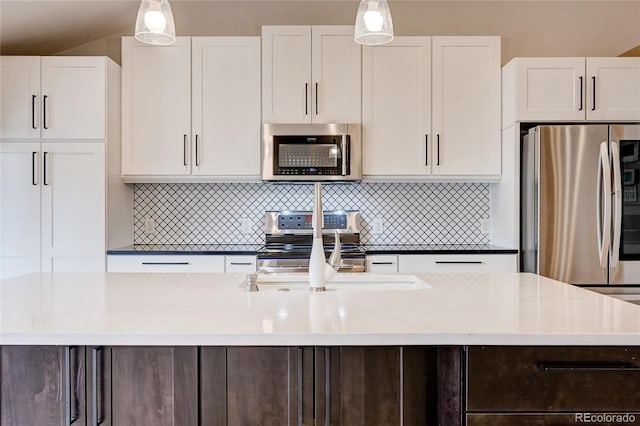 kitchen with white cabinetry, tasteful backsplash, appliances with stainless steel finishes, and decorative light fixtures