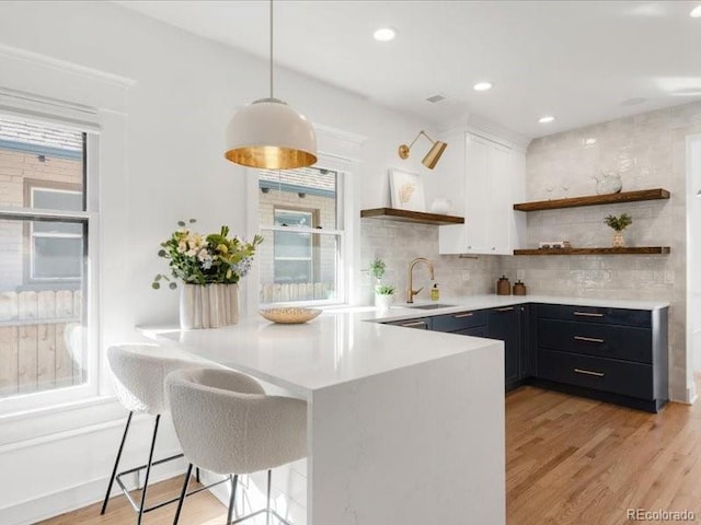 kitchen with open shelves, plenty of natural light, light countertops, and a sink