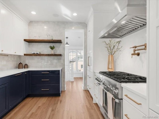 kitchen featuring light countertops, range with two ovens, light wood-style flooring, range hood, and white cabinets