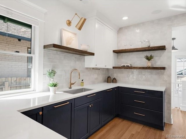 kitchen featuring open shelves, a sink, light wood-style floors, white cabinets, and light countertops