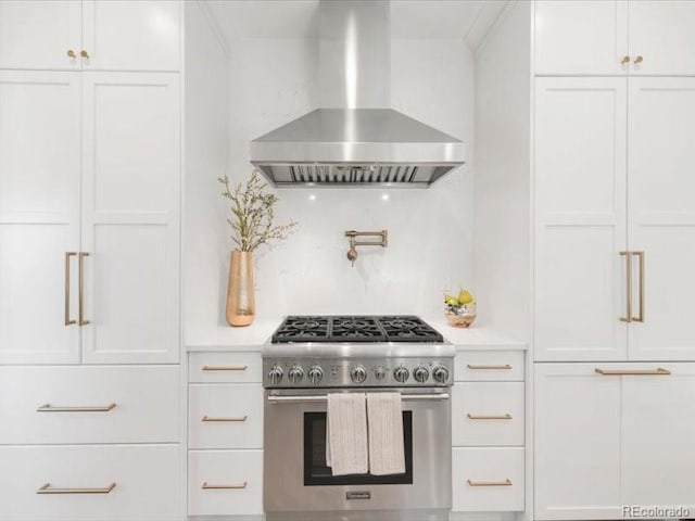 kitchen featuring white cabinets, wall chimney exhaust hood, and high end stainless steel range