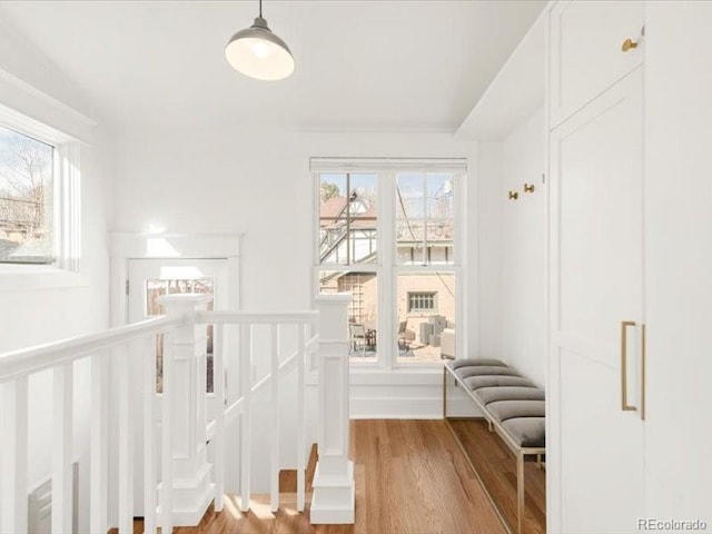 corridor featuring a wealth of natural light, an upstairs landing, and wood finished floors