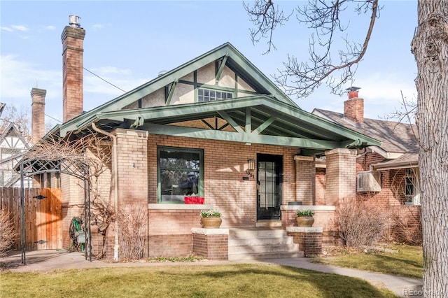 view of front of property featuring fence, a porch, a chimney, a front lawn, and brick siding