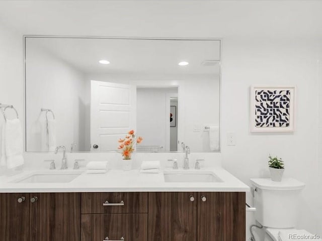 bathroom with double vanity, toilet, and a sink