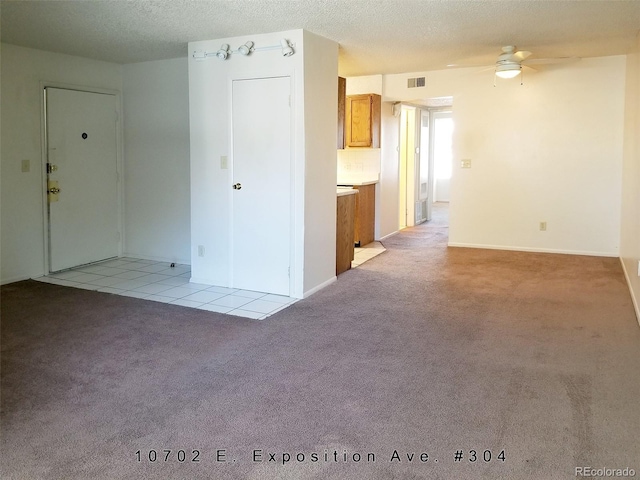 unfurnished room featuring a textured ceiling, ceiling fan, and light carpet