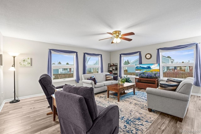 living room with light wood-style flooring, baseboards, and a ceiling fan