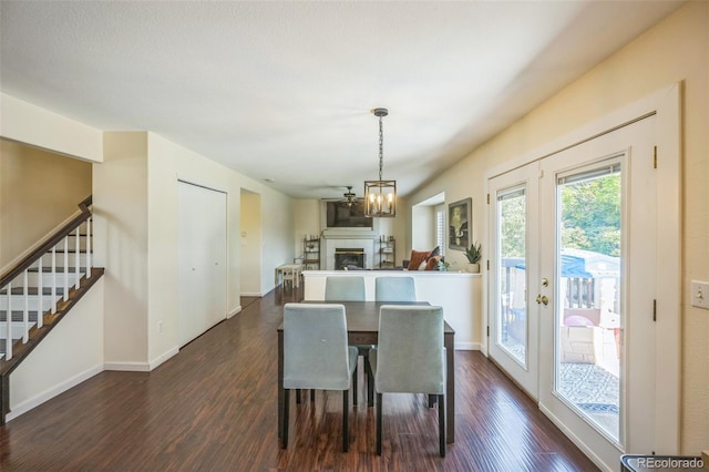 2695 Woodrose Pl, Highlands Ranch, CO 80129 - dining space featuring stairway, dark wood-style flooring, a fireplace, and a chandelier