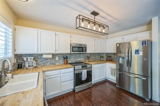 2695 Woodrose Pl, Highlands Ranch, CO 80129 - kitchen with appliances with stainless steel finishes, tasteful backsplash, wood counters, white cabinetry, and hanging light fixtures